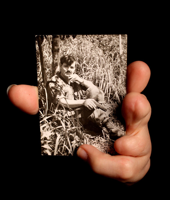 Portrait - 1st place - Heather Bowser, of Canfield, is a child of Agent Orange. Bowser was born with three missing fingers on the left hand and is missing part of one finger on her right hand. Here she holds a picture of her father William A. Morris, in Vietnam. Bowser was also born without her right leg. Bowser's father, who fought in Vietnam, always believed he was exposed to the chemical and passed it onto Heather. Bowser's father died when he was 50 years old of heart disease which they attribute to Agent Orange. (Lisa DeJong / The Plain Dealer)