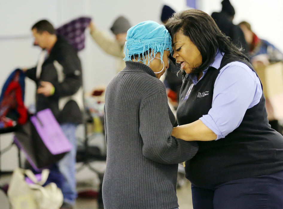 General News - 1st placeWhile folks dig through clothing donations, Carmen Allen (right) of IMPACT Community Action stops to pray with Teresa Farmer during the U.S. Department of Housing and Urban Development's required yearly Point-in-Time Count at Veterans Memorial. Allen and Farmer have known each other since middle school but haven't seen each other for several years. In addition to taking a count of Columbus' homeless population, the event offered support services from numerous community organizations, like IMPACT, as well as health screenings.  (Adam Cairns / The Columbus Dispatch)