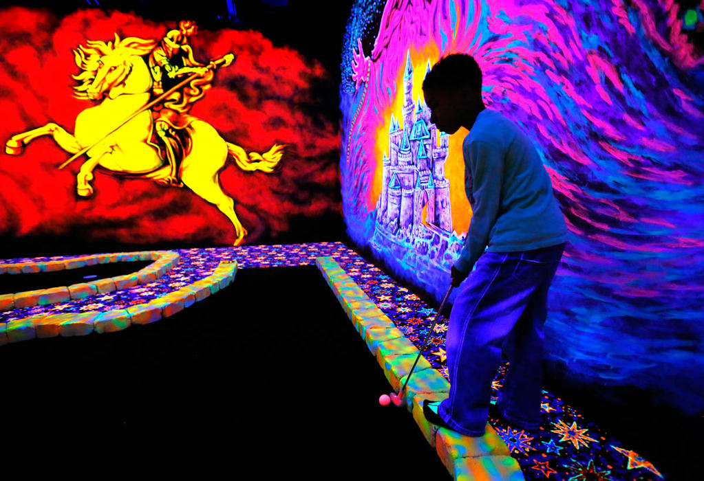 Feature - 3rd place - Justin Mitchell, 8, lines up a shot while playing glow-in-the-dark mini golf at Sylvania Playland.  The third grader was enjoying another day off from Stranahan Elementary School.  (Andy Morrison / The (Toledo) Blade)