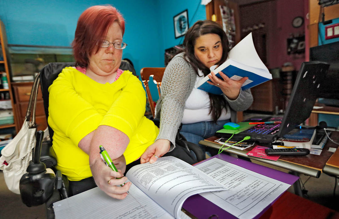 General News - 2nd place - Independent home health care worker Juanita Bobo has her hands full helping Amber Radune with her college studies. Juanita has to position the pen in Amber's hand, turn the pages and hold open the text book for Amber who has a congenital illness that severely affects her joints and motion.  New Medicare rules may cause Amber to lose benefits that allow her to live at home.  (Chris Russell / The Columbus Dispatch )