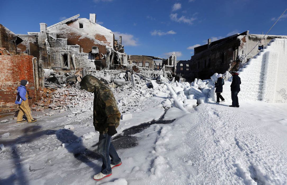 Spot News - 3rd place - Waverly residents (from left) Loren Oyer, Steve Topping, Tracy Murray and Blake Murray stop to get a glimpse of the ice-blanketed remains of the Emmitt House as it still smolders a day after being destroyed by a fire. The restaurant, which was built in 1861 as a hotel by entrepreneur James Emmitt, had just reopened in August after being purchased and renovated by new owner Pam Ison. One of numerous residents to survey the damage, Tracy came to see the remains of the establishment in which she met her husband.  (Adam Cairns / The Columbus Dispatch)