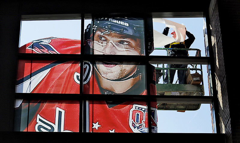 Feature - 2nd place - Josh Gallant an employee of CGS Imaging installs the image of Washington Capital's Alexander Ovechkin on the west side of Nationwide Arena as preparations for the NHL All Star game continue in the Arena District.   (Chris Russell / The Columbus Dispatch )