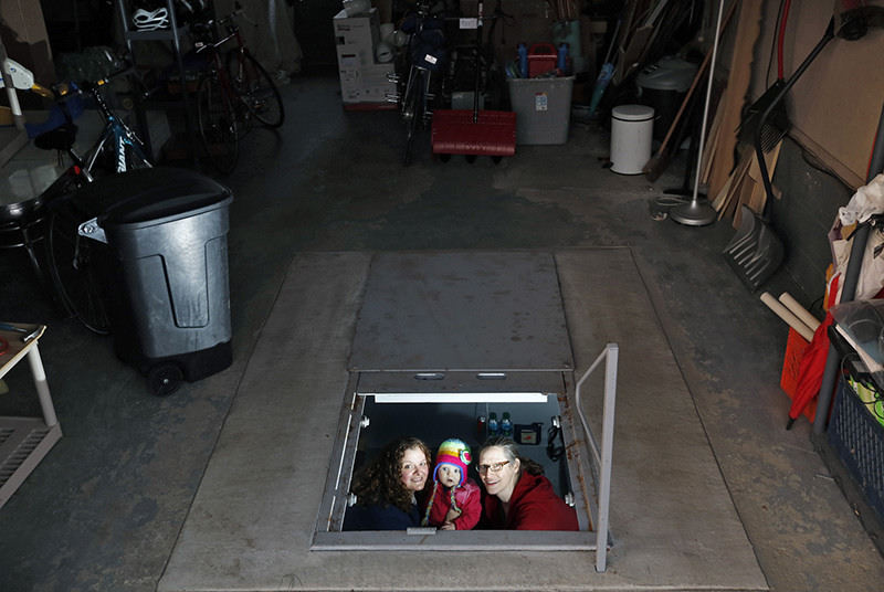 Portrait - 1st place - Mary Kirstein (left) and Claudia Anderson (right) and their daughter Lela Kirstein sit in their below ground shelter in their garage at their house in Hilliard.  The below ground shelter was mostly paid for by a Ohio EMA grants through the Ohio Safe Room Rebate Program.   (Kyle Robertson / The Columbus Dispatch)