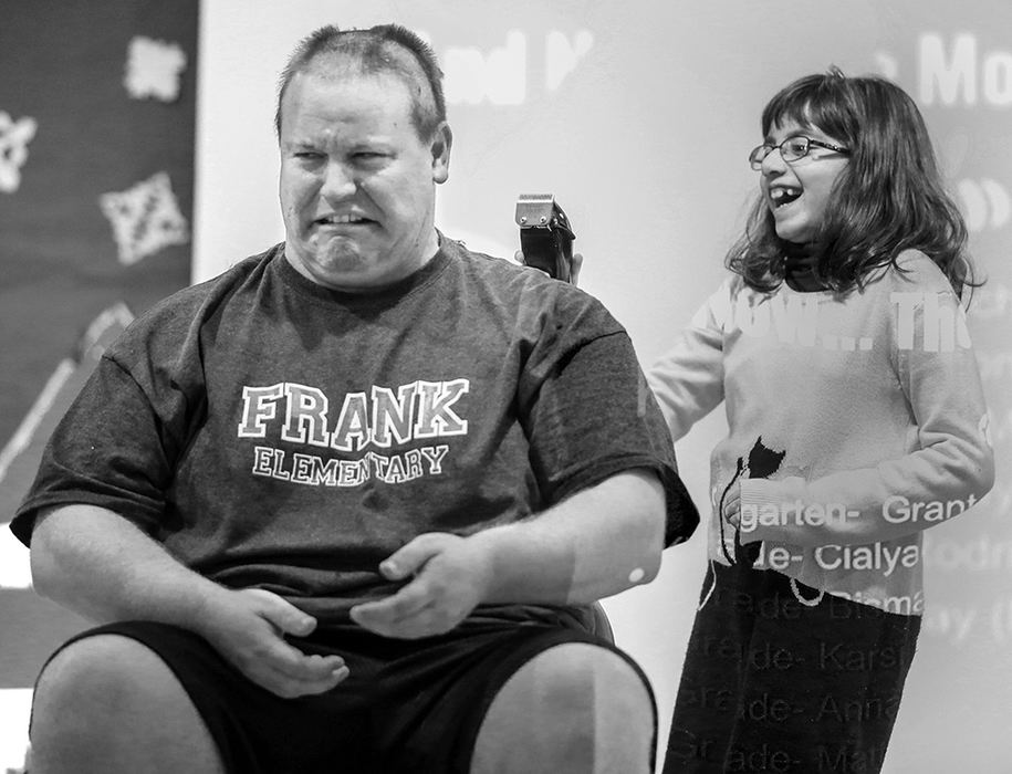 Feature - 3rd place - Second grader Bismah Gill laughs as she shaves the head of Frank Elementary School Principal Chad Warnimont in Perrysburg. Students earned the semester incentive of shaving his head by earning Jacket Way tickets for being respectful, responsible and ready.  (Andy Morrison / The Blade)