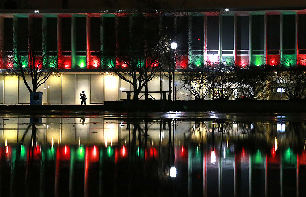 Feature - HM -  A pedestrian walks along Fountain Avenue as the Holiday lights on the Key Bank building are reflected in the water standing on the City Hall Plaza. (Bill Lackey / Springfield News-Sun)