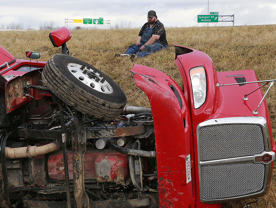 Spot News - 1st place - The driver of a semi tractor-trailer sits on the ground looking at his truck after he lost control and rolled it on the exit ramp from eastbound I-70 to southbound I-675. The driver was not injured in the crash.  (Bill Lackey / Springfield News-Sun)