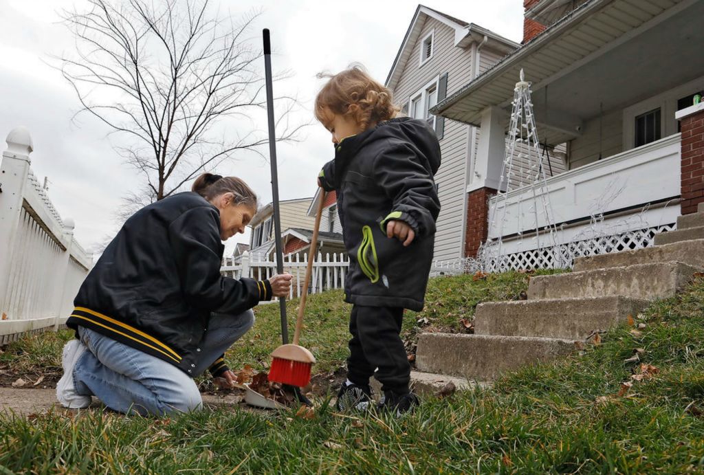 General News - HM - Monessa Dotter has some help from her grandson Jerimiah Lowe, 2, as she cleans up fall leaves at her Hilltop home along S. Eureka Ave.  where she has lived for 5 years. Monessa says the home behind despite its nice exterior has been abandoned for some time and believes there are now animals in the house.The city has announced a new a new plan for the neighborhood called Envision Hilltop. (Eric Albrecht/The Columbus Dispatch)