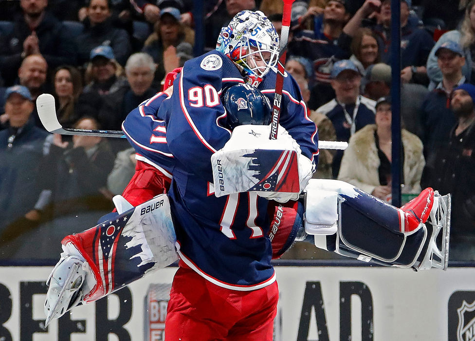 Sports Feature - 2nd place - Columbus Blue Jackets goaltender Elvis Merzlikins (90) jumps into the arms of left wing Nick Foligno (71) after beating Carolina Hurricanes 3-2 in their NHL game at Nationwide Arena in Columbus. (Kyle Robertson/The Columbus Dispatch)