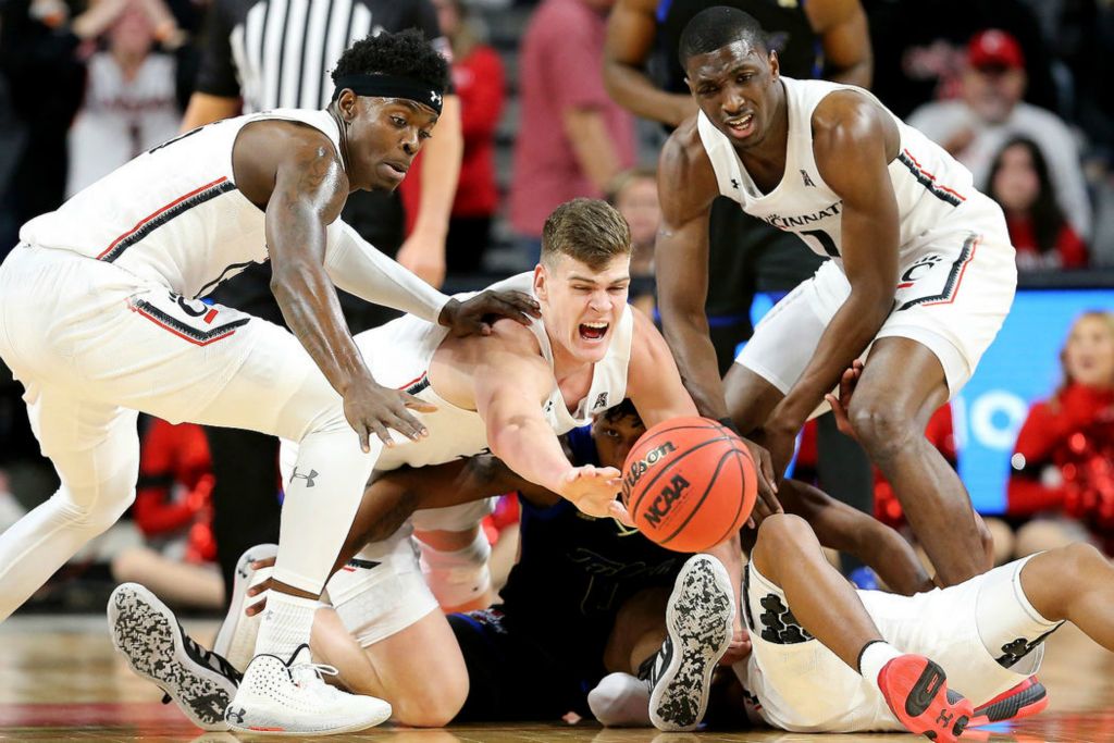 Sports - HM - From left: Cincinnati’s Trevon Scott (13) and Chris Vogt (33), Tulsa’s George Christopoulos (13), and Cincinnati’s Mika Adams-Woods (3) and Keith Williams (2) compete for a loose ball during the first half of a game at Fifth Third Arena in Cincinnati.  (Kareem Elgazzar/The Cincinnati Enquirer)