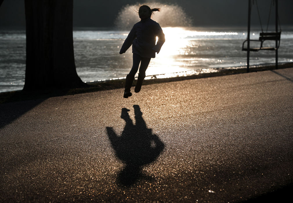 Feature - 2nd place - A young girl is silhouetted in the evening sun as she skips along the roadway in Snyder Park to catch up to her father.  (Bill Lackey / Springfield News-Sun)