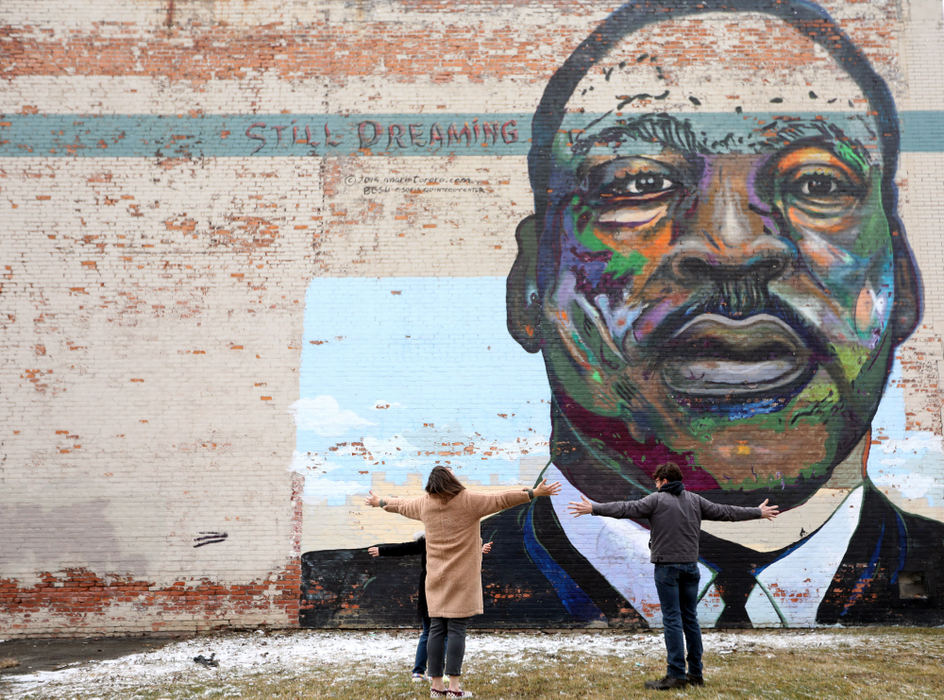 Feature - HM - Gianna Nussbaum, 8,(left) and her parents Brandi and Eric Nussbaum spread their arms in praise while visiting the mural of Martin Luther King, Jr. by Mario Acevedo Torero and BGSU students (2014) on Broadway St.. The family usually celebrates Martin Luther King Jr. Day by attending services or special events but due to coronavirus restrictions events were either held online or canceled. (Amy E. Voigt / The Blade)