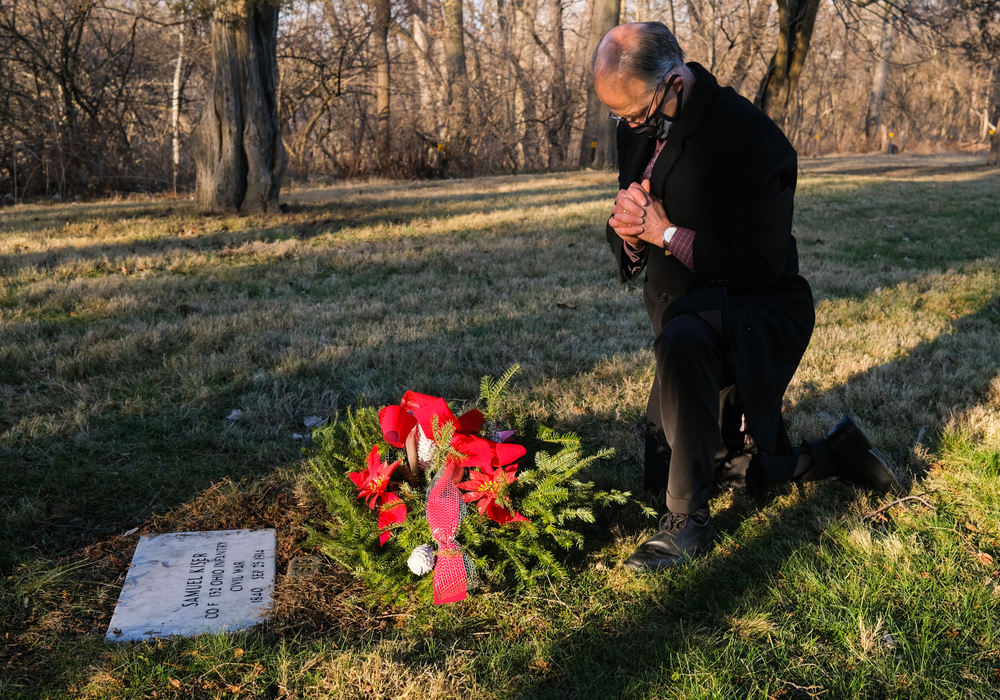 General News - 3rd place - Jim Szakovits, General Manager of Ottawa Hills Memorial Park, places a grave pillow on a veteran’s grave  at the Toledo State Hospital Cemetery. Mr. Szakovits brought 6 blankets, 5 pillows, and 4 wreaths to be placed on the graves of former patients of the Toledo State Hospital that are unclaimed by family members. The donation is to raise awareness for the Toledo State Hospital Cemetery Reclamation Project. There are about 2,000 people buried in the Toledo State Hospital Cemeteries. (Jeremy Wadsworth / The Blade)