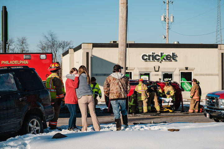 Spot News - 2nd place - The driver of a vehicle involved in a two-car motor vehicle crash, in red, is embraced as occupants of the other vehicle are extricated by New Philadelphia Fire Department personnel in front of Cricket Wireless on West High Ave. in New Philadelphia.  (Andrew Dolph / The Times Reporter)