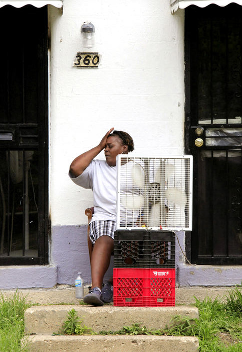 General News - 1st place - Teloa Lee tries to cool off from the heat and humidity with a fan on the stoop of her apartment which has no windows that can be opened.  (Jeff Hinckley / The Columbus Dispatch)