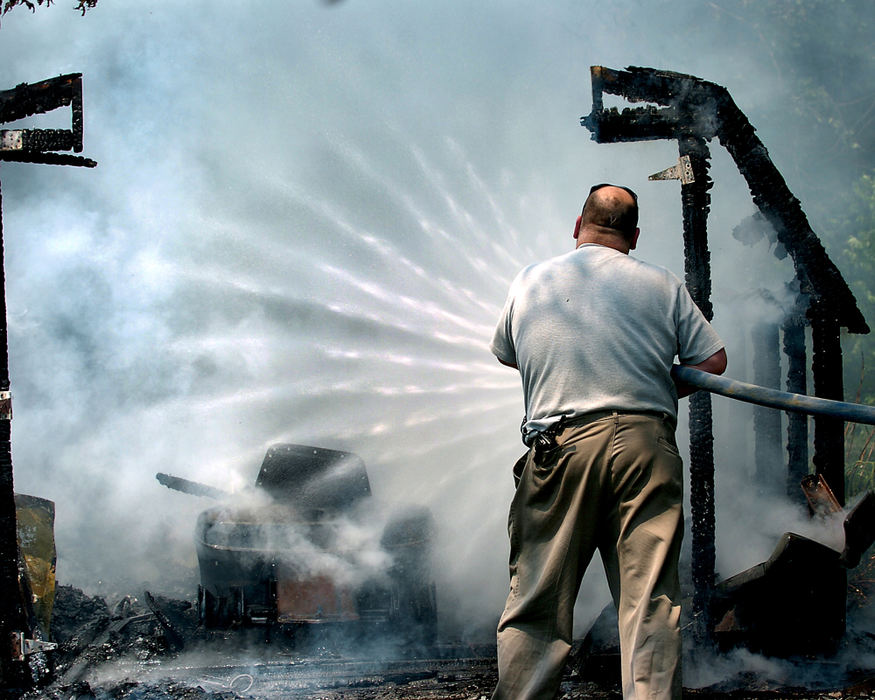 Spot News - 1st place - North Kingsville fire chief Brian Lehtonen pours water on a shed fire at 2900 Bugby Road Ext. in North Kingsville. Ashtabula Township F.D. also responded to the small, but intense blaze. (William A. West / The (Ashtabula) Star Beacon)