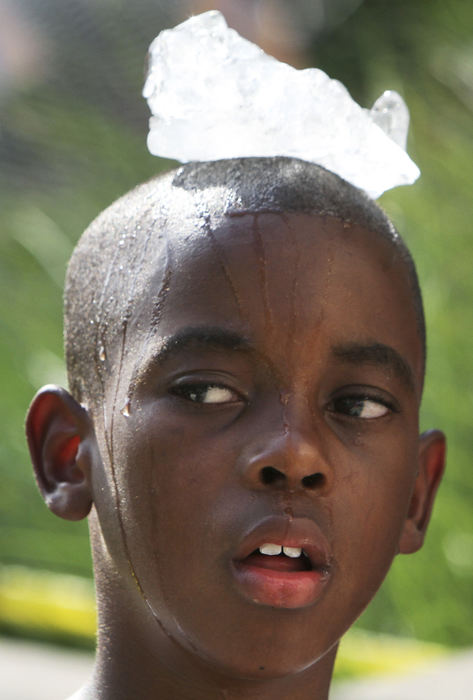 Story - 2nd place - Kalei Nelms (9) of Columbus puts a chunk of ice on his head to cool down during the Red, White and Boom Parade in downtown Columbus. (Neal C. Lauron / The Columbus Dispatch)