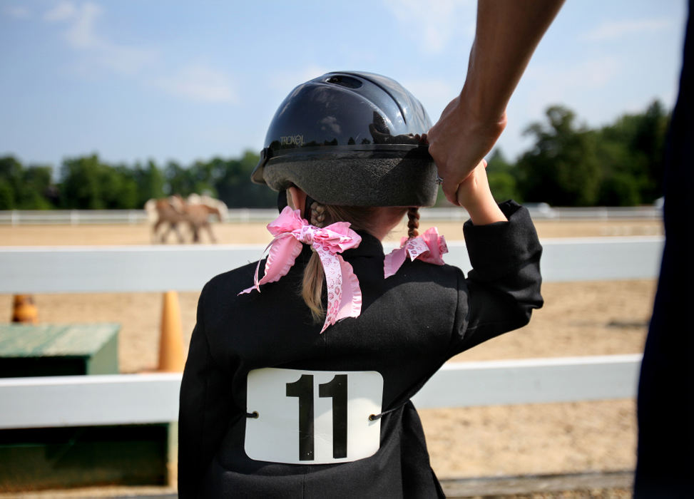 Feature - 2nd placeSporting her pink ribbons on her braids, Sydney Corcoran, 4, of Auburn Township, holds the hand of her mother, Jessica, just before her " Beginner Trail" and "Beginner Equitation" riding competition at the Chagrin Valley Hunter Jumper Classic at the Cleveland Metroparks Polo Field in Moreland Hills. Corcoran and other riders with disabilities from the Fieldstone Farm Therapeutic Riding Center are given the opportunity to demonstrate their abilities on horseback at the show.  ( Lisa DeJong / The Plain Dealer)