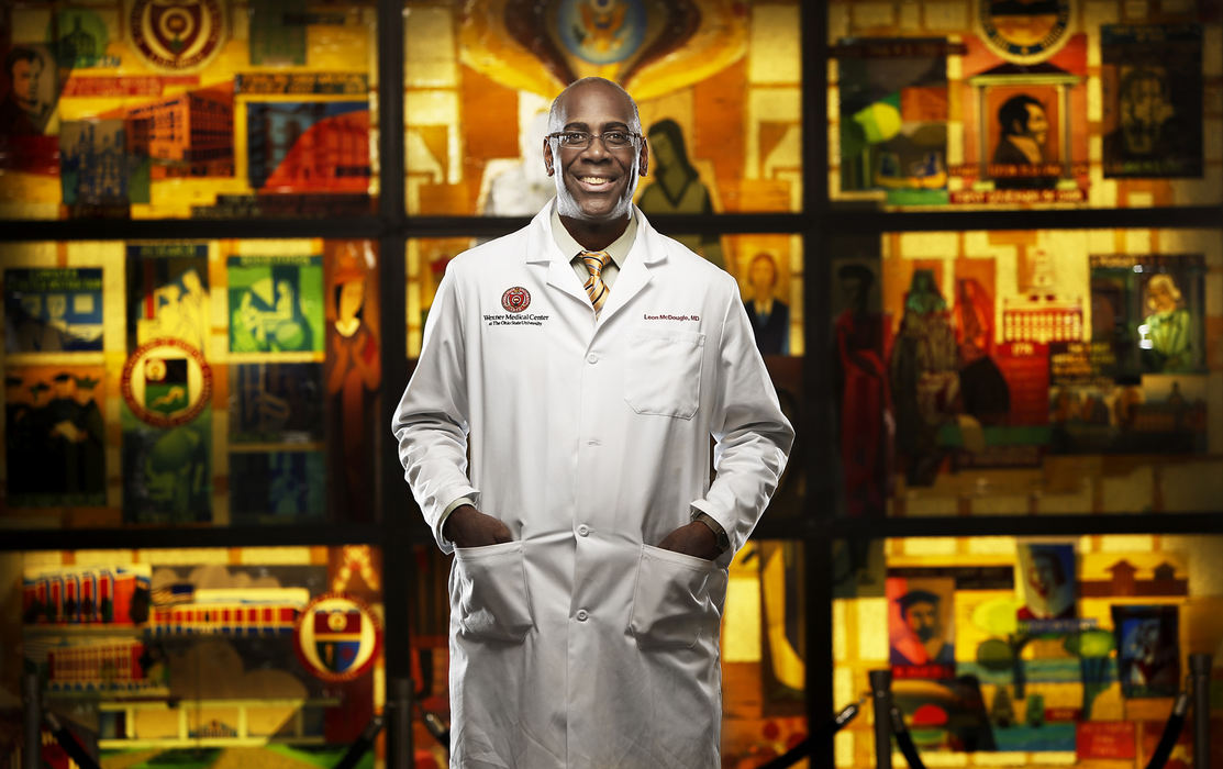 Portrait - 3rd placeDr. Leon McDougle poses for a photograph in Meiling Hall in front of a glass mural by Columbus artist Cutiss Inscho that portrays the heritage of the College of Medicine at Ohio State University. McDougle has been appointed as the Wexner Medical Center's first ever chief diversity officer. Ohio State has three times more minority students than the national average but McDougle plans to collaborate across all the OSU medical colleges to bring an even more diverse group to the faculty as well as student body.  (Eamon Queeney / The Columbus Dispatch)