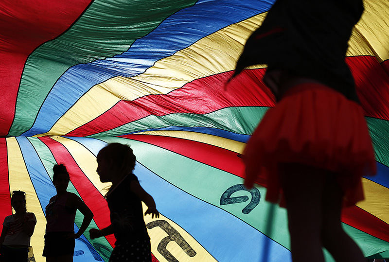 Feature - 2nd place - Kids play in the Roochute, a giant parachute owned by Ron Holgado, of Old Town East, who brought it for people to play with, as they wait for the fireworks to start near North Bank Park in downtown Columbus.  (Eamon Queeney / The Columbus Dispatch)