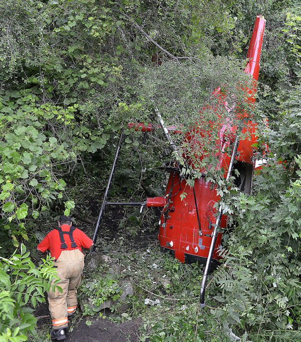 Spot News - HM - A member of the West Liberty Fire Department climbs up a ravine as he tries to reach a helicopter that crashed near Liberty Hill Golf Course in Logan County and came to rest on a wooded hillside. The pilot was transported to the hospital and later taken by medical helicopter to Columbus.  (Bill Lackey / Springfield News-Sun)