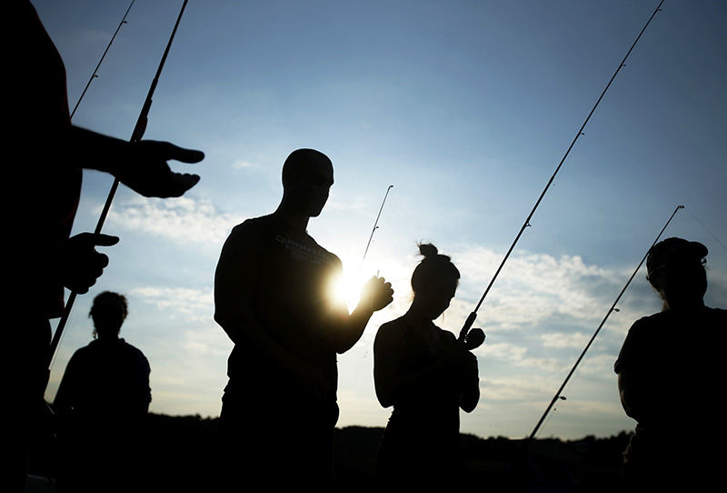 Feature - HM - Campers prepare their fishing poles at Stratford Ecological Center's first Adult Farm Camp. Participants spent the day learning farm chores and skills and spending the night camping out on the land in Delaware. Campers ages ranged from 20s-70s.  (Leah Klafczynski / The Columbus Dispatch)