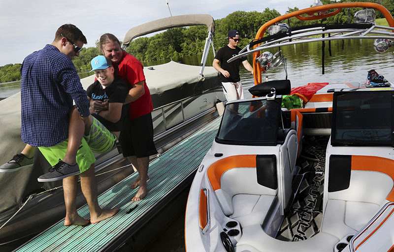 Story - HM - Drew Ridgway (left) and Jim Shawley carry Adam Helbling into Jim's boat for a afternoon on the Scioto River .Adam was out for a afternoon while some friends were wake boarding on the river. (Eric Albrecht / The Columbus Dispatch)