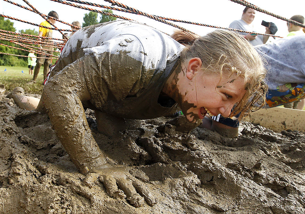 Feature - 3rd place - Mariah Whetstone crawls through the mud on one of the obstacles during the National Trail Parks and Recreation's Mud Mania.  (Bill Lackey / Springfield News-Sun)