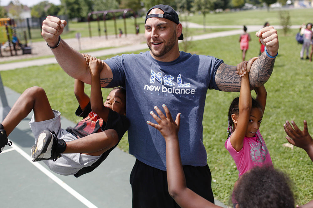 SPFeature - HM - Ohio Machine goalkeeper Scott Rodgers holds up campers as they swing from his biceps before the start of the Urban Lacrosse Summer Clinic at Barack Community Recreation Center in Columbus. The clinic is a joint effort between U.S. Lacrosse and Columbus Recreation and Parks. (Joshua A. Bickel / The Columbus Dispatch)