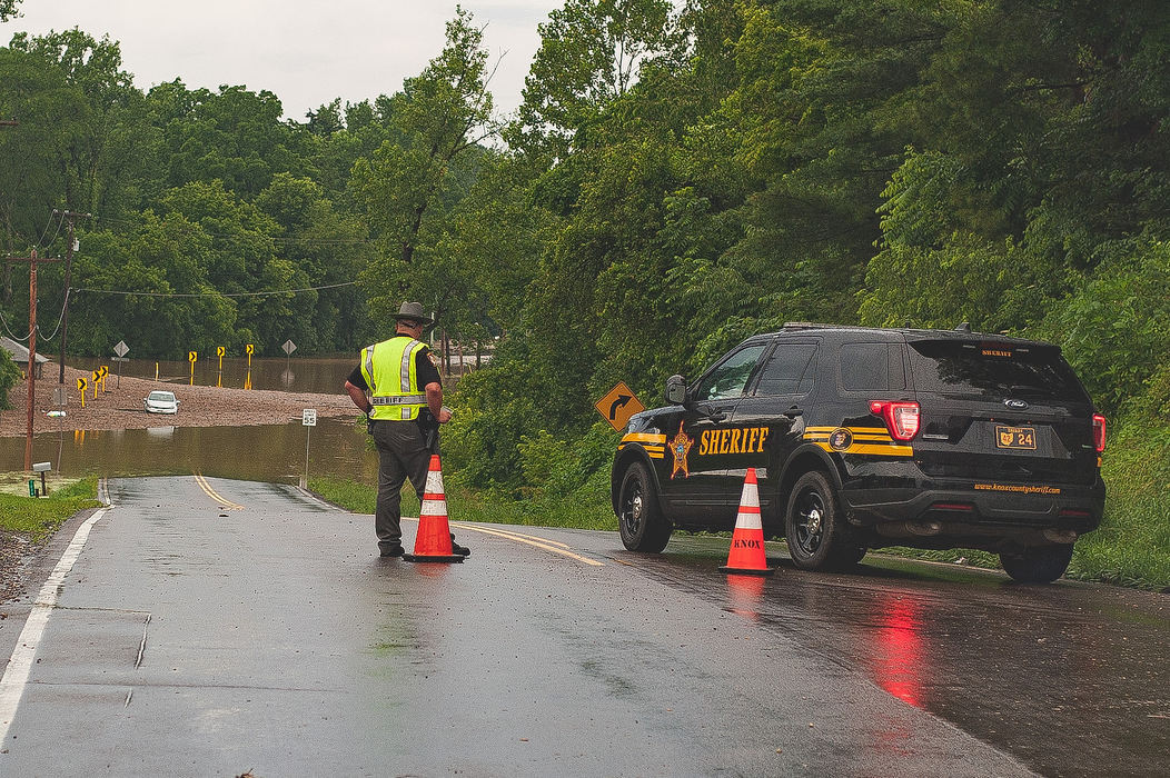 Spot News - HMKnox County Sheriff’s Office deputy Dan Selby looks at a car surrounded by flood waters on Ohio 3/US 36 south of Mount Liberty. The driver was lead to safety by the Mount Vernon Fire Department. Officials closed the road for several hours.  (Joshua Morrison/Mount Vernon News)