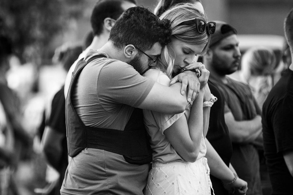 General News - 2nd place - Officer Anthony Dia's cousin Moustafa Rahal (left) hugs his girlfriend Molly Haskin during a candle-light vigil for Toledo Police Officer Anthony Dia in the Kroger parking lot in Bedford Township, Michigan.  Moustafa arrived to the vigil wearing the bullet proof vest Officer Anthony Dia gave him after he finished part of his training to become a police officer.  (Rebecca Benson / The Blade)