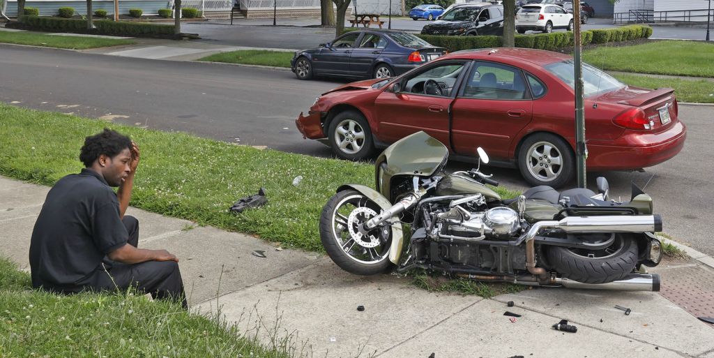 Spot News - 1st place - The driver of a car sits in the grass after he struck a motorcyclist at the intersection of North Limestone Street and East Cecil Street. The rider of a motorcycle was transported by medical helicopter to Miami Valley Hospital with a severe leg injury.  (Bill Lackey / Springfield News-Sun)