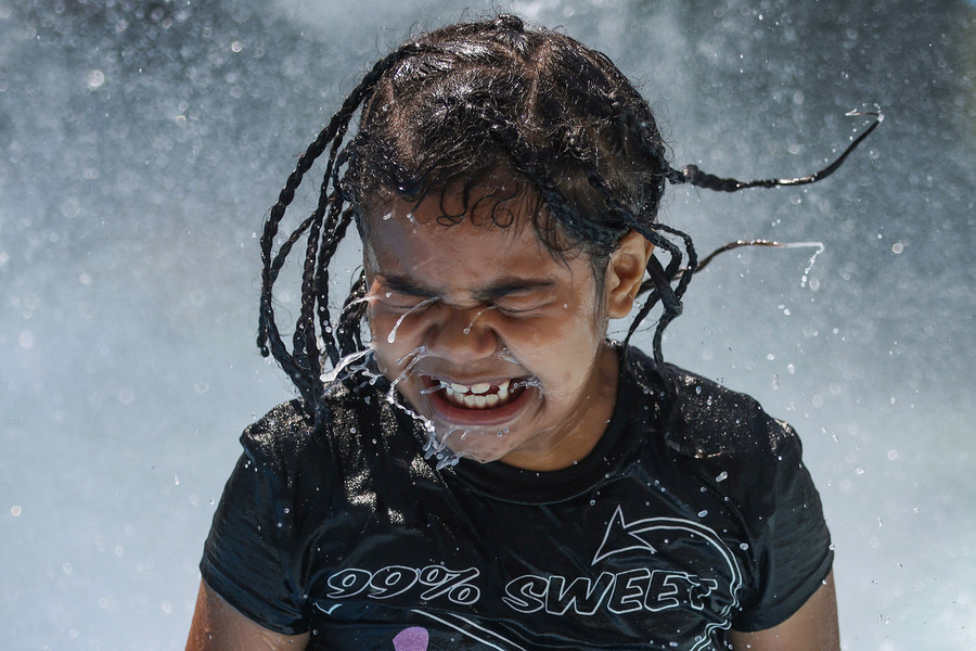 Feature - 3rd place - Ashlynn Collmar, 7, shakes the water off of her face as she enjoys the first day of the Savage Park splash pad being open after being closed for health inspections in Toledo. (Rebecca Benson / The Blade)