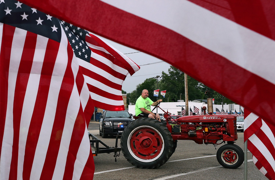 General News - HM - A participant in this year’s Garrettsville Tractor Parade is framed by the Stars and Stripes as he shows off his Farmall Super C during the parade through town. (Jeff Lange / Akron Beacon Journal)