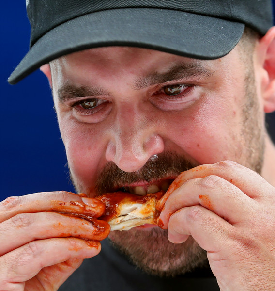 Portrait - 1st place - Tears well up in the eyes of Kyle Fisher of Hiram as he competes in the hot wing eating contest during the Garrettsville Summerfest. Kyle completed the challenge in a three-way tie to win $100. (Jeff Lange / Akron Beacon Journal)