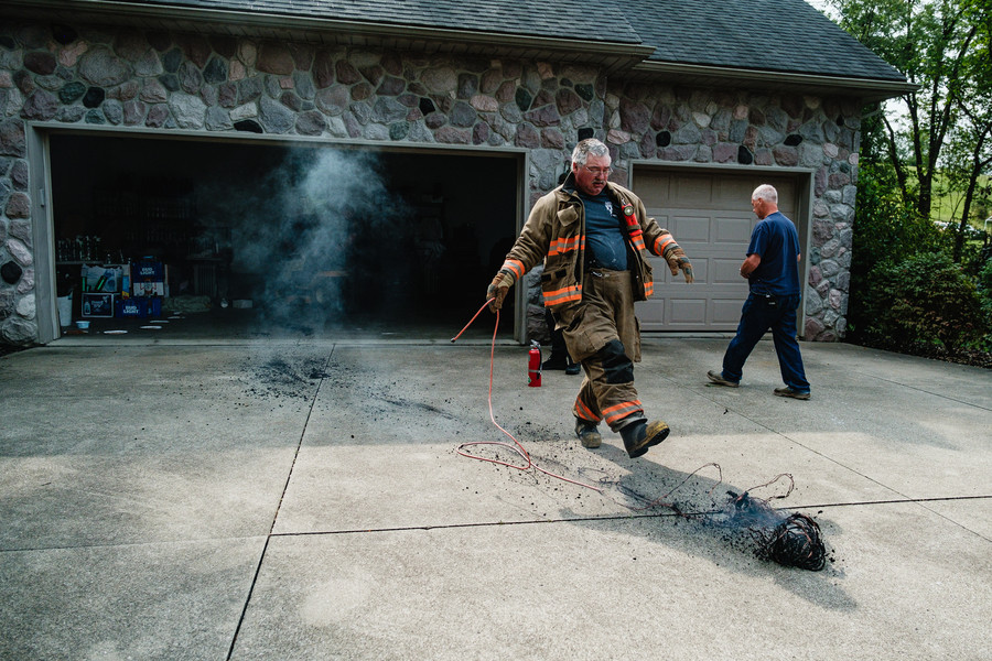 Spot News - 1st place - Mineral City firefighter Jim Daugherty kicks a smoldering extension cord that caught fire in the garage of a home on Dessecker Dr NE, in Fairfield Township. (Andrew Dolph / The Times Reporter)