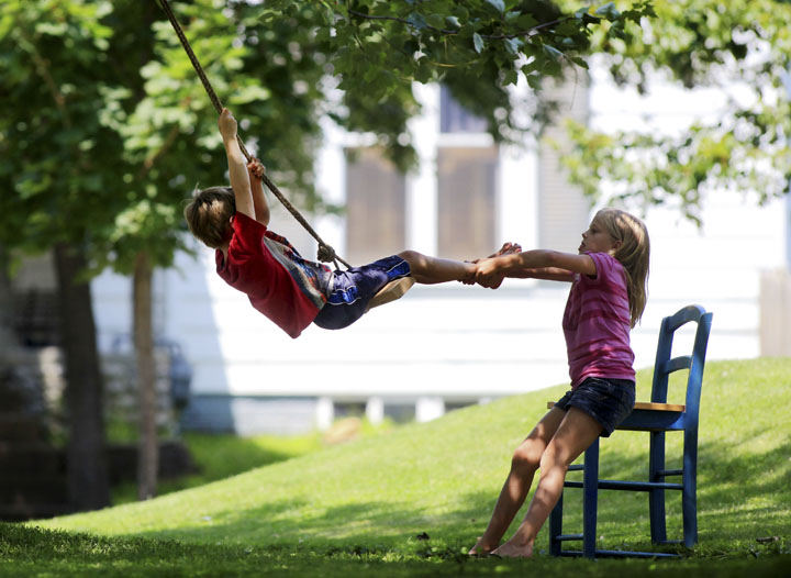 Feature - HM - Emma Moyer (right) gives neighbor  Gideon Doan a pull on a swing that her brother Chris Moyer had built along with some other neighbor kids near there homes in Bremen in Fairfield County. (Eric Albrecht / The Columbus Dispatch)