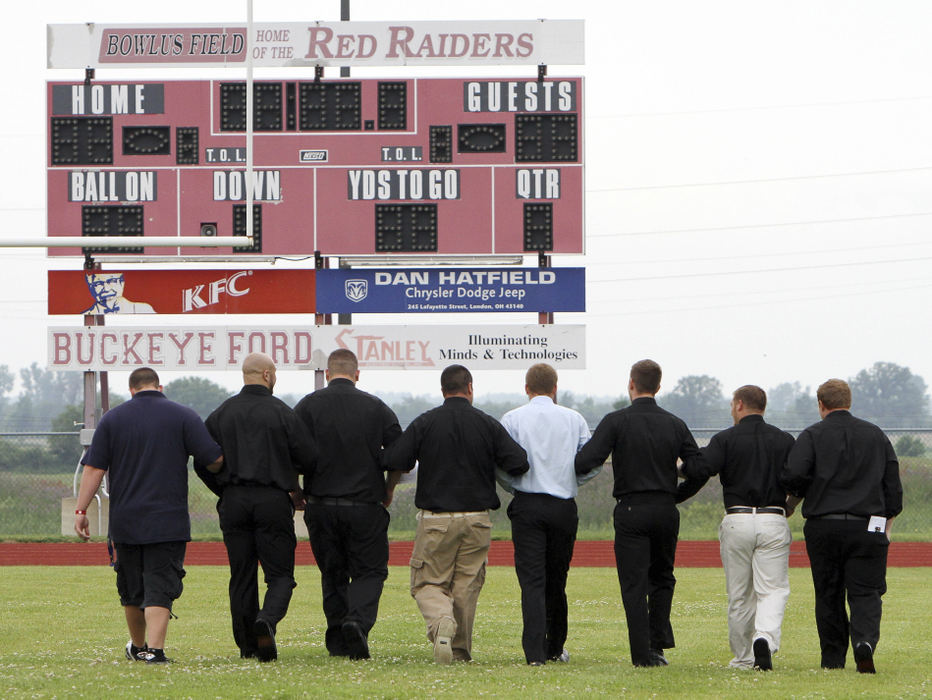 Story - 3rd place - Former football teammates of Marine Lance Cpl. Joshua McDaniels walk arm in arm in a last ceremonial walk across the London High School football field after friends and family release balloons in his McDaniels' memory on the 50 yard line after the funeral service. McDaniels was killed in Afghanistan by a roadside bomb.  (NEAL C. LAURON / COLUMBUS DISPATCH)