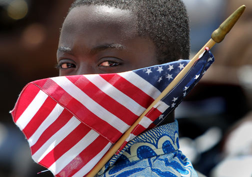 Portrait - 3rd place - Todee Yonly, 11, holds a flag while his parents, Moses and Helen Yonly, are naturalized as U.S. Citizens during the Flag Day 2011 & U.S. Army 236th Birthday & Naturalization Ceremony in front of the Rock and Roll Hall of Fame and Museum.Twenty-nine people, from countries as far away at Romania and Zimbabwe, were naturalized by U.S. District Court Judge Christopher Boyko as United States citizens. (Lisa DeJong / The Plain Dealer)