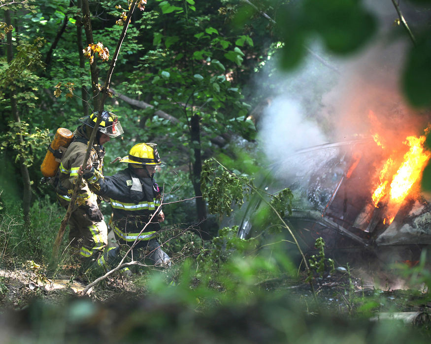 Spot News - 3rd placeSheffield and Plymouth firefighters make their way down a steep hill to a burning car in Plymouth Township. Phillip Scheanon, 17, miracuously escaped injury after he rolled down a very steep embankment in his mother's 1998 Buick Regal. Scheanon lost control of the car on a gravel section of Hadlock Road in Plymouth Township. The car traveled between a guard rail and a large tree; removing the bark from the tree before rolling about 75 feet down the hill where they came to a stop. Smoke was pouring from the car as Scheanon climbed out of the car and climbed back up the embankment and into the arms of Vickie Lee. Lee had called 911. The car burst into flames and was fully engulfed when firefighters from Plymouth and Sheffield fire departments arrived at the scene.  (William A. West / Wwest News Service (WNS))