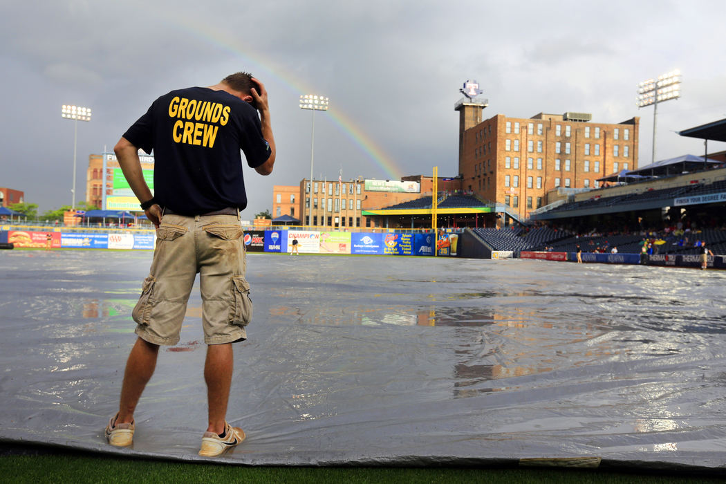 Sports Feature - 1st placeA rainbow forms over Fifth Third Field as grounds crew member Christopher Chapinski rubs the rain out of his hair while he helps hold down the tarp during a rain delay as the Toledo Mud Hens prepare to play the Louisville Bats. (Andy Morrison / The Blade)