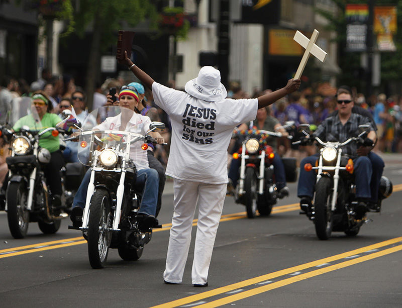 General News - HM - A single protestor is outnumbered by an oncoming group of the parade's motorcyclists during the annual Stonewall Columbus Pride Parade. (Jenna Watson / The Columbus Dispatch)