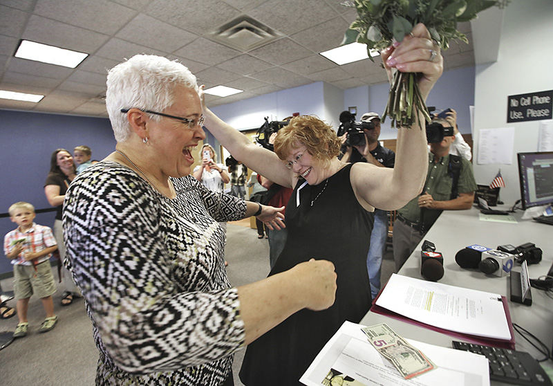 General News - 2nd place - Waiting at the Probate Court for the Supreme Court decision on same sex marriage, Mindy Ross (left) and Jimmie Beall celebrate at the counter after putting down their money to finally receive a marriage license  on June 26. They were the first in line after the U.S. Supreme Court struck down the ban against same sex marriage.   (Chris Russell / The Columbus Dispatch)