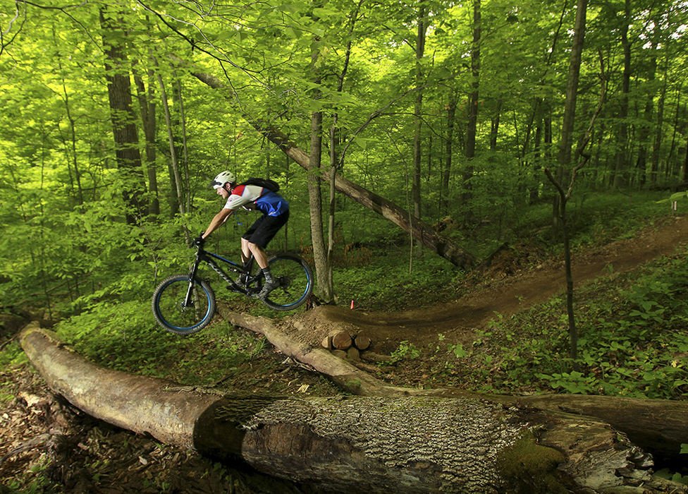 Sports - 2nd place - A rider tackles a jump over a pair of fallen trees during the 2016 AOA/BikeFettish Mayhem Enduro mountain bike race at the Wilds mountain bike trails in Cumberland. The race featured five timed sections over a 13 mile race. (Chris Crook / Zanesville Times Recorder)