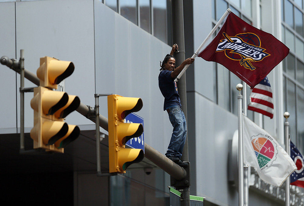 aStory - 1st place - Cleveland Cavalier fans wait to watch the NBA Championship parade on a light post on East 9th Street in downtown Cleveland. (Kyle Robertson / The Columbus Dispatch)