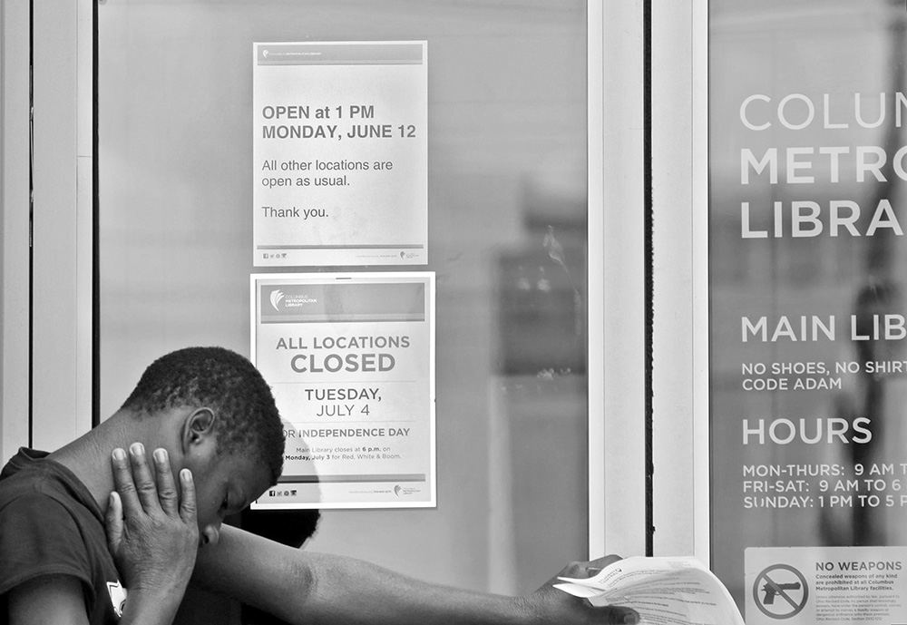 General News - 3rd place - A man waits at the door of the downtown Columbus Metropolitan Library which opened at later that usual, at 1 p.m.  following a shooting inside the library the day before.  (Barbara J. Perenic / The Columbus Dispatch)