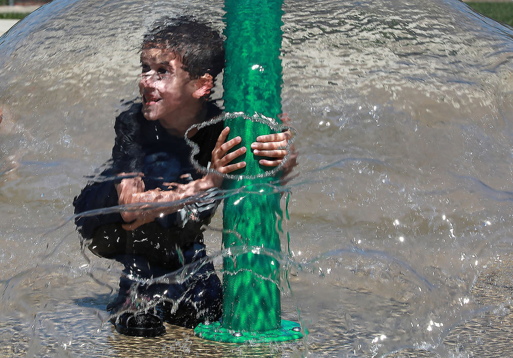 Feature - HMOliver Johnston plays under an umbrella of water at the Sprayground at Snyder Park. (Bill Lackey/Springfield News-Sun)