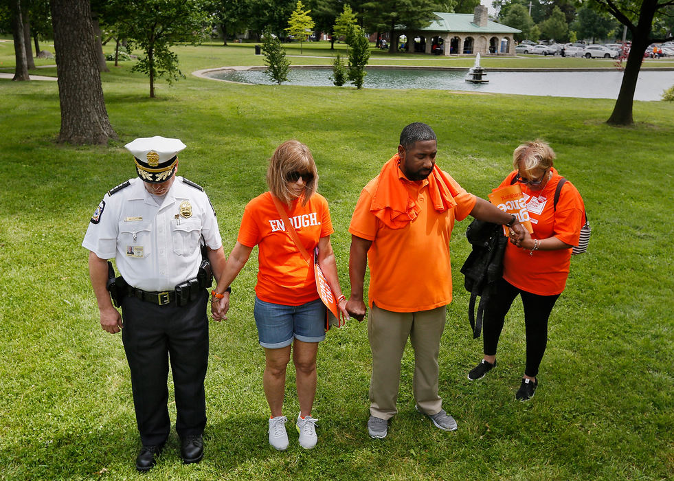 General News - HMColumbus Police Chief Tom Quinlan, Mindy Hall, Michael Cole and Celeste LaCour-Belyn hold hands during a prayer offered by Pastor Michael Young from City of Grace Church at Westgate Park in honor of Wear Orange Weekend. The rally brings awareness to gun violence though out the Columbus community. (Eric Albrecht/The Columbus Dispatch)