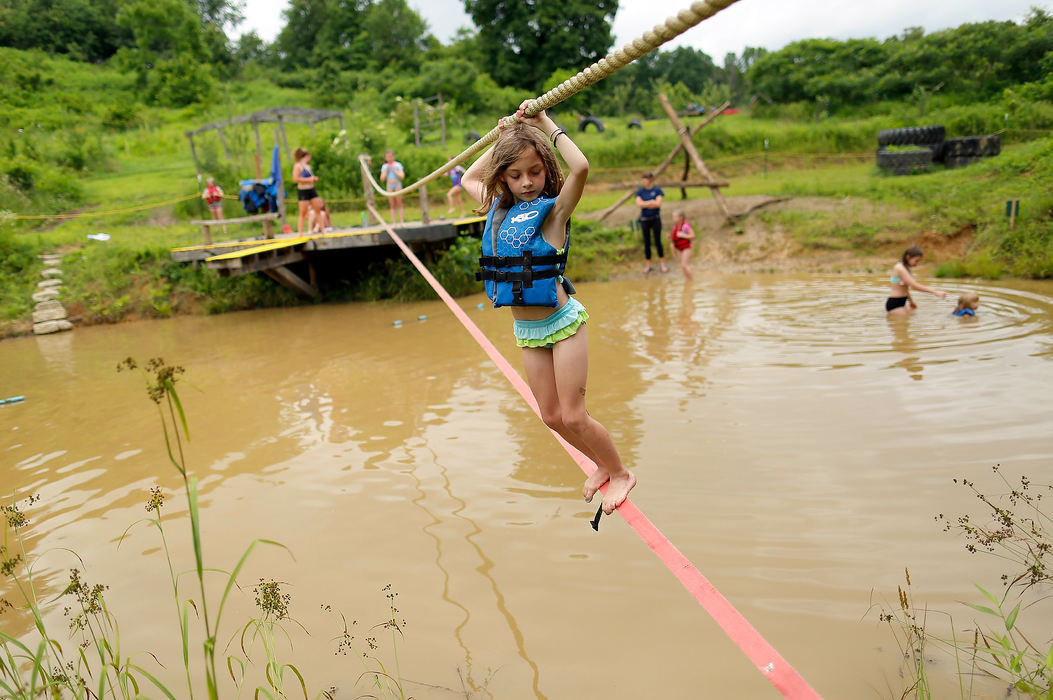 Story - 1st placeNicole Vorisek, 7, carefully walks across the slack line over the swimming pond during Rising Appalachian Warriors Camp at Solid Ground Farm in Millfield, Ohio. RAW Camp helps to teach life skills and to give kids a hands-on understanding of nature. (Adam Cairns/The Columbus Dispatch)