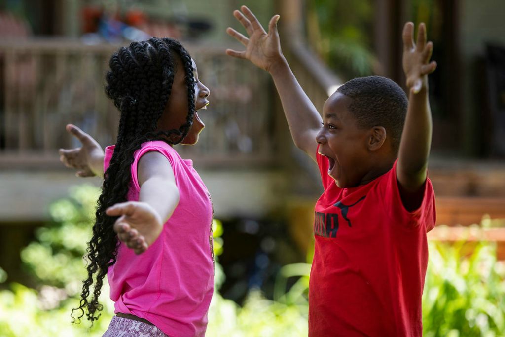 Feature - HM - Ahei'Ah Greer, 11 and her brother Malachi, 9, hold out their arms before hugging while helping set up tables sell different items during the unofficial Old West End Festival in the Old West End in Toledo. (Rebecca Benson / The Blade)