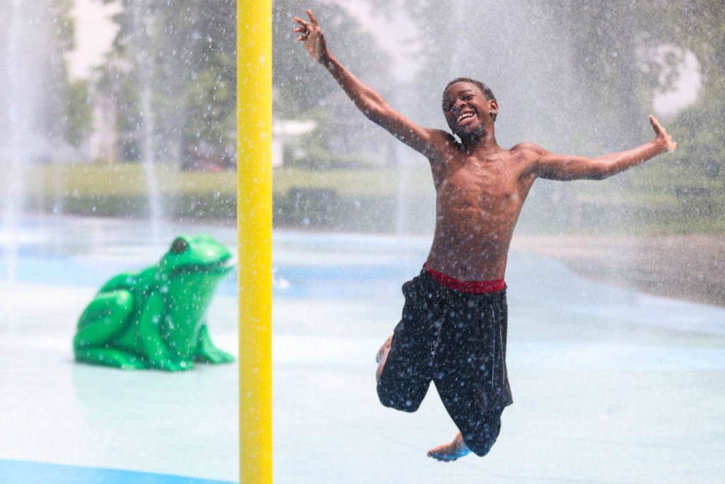 Feature - HM - Ronald Munn, 12, jumps in the water at the Savage Park Splash Pad in Toledo. (Rebecca Benson / The Blade)